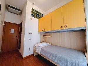 a small bedroom with a bed and yellow cabinets at Hotel Butterfly Wellness & Spa in Rimini