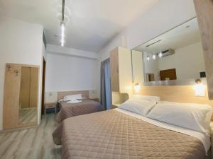 a hotel room with two beds and a mirror at Hotel Butterfly Wellness & Spa in Rimini