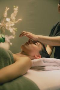 Eine Frau, die auf einem Bett mit der Hand auf dem Kopf liegt. in der Unterkunft Astoria Resort in Riva del Garda