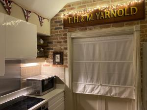 eine Küche mit Mikrowelle und ein Fenster mit Schild in der Unterkunft Enchanting 1 Bedroom Home with Kitchen in Saffron Walden