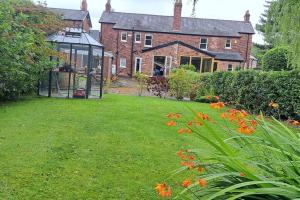 a house with a greenhouse and a yard with flowers at Stunning 3BD Victorian House in Bramhall Village in Bramhall
