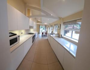a large kitchen with white cabinets and a long hallway at Stunning 3BD Victorian House in Bramhall Village in Bramhall