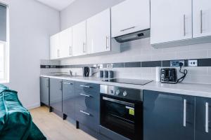 a kitchen with white cabinets and a black oven at Stylish Apartment located in the City Centre of Liverpool - Sleeps 5 in Liverpool