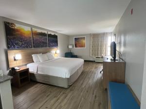a hotel room with a bed and a television at Days Inn by Wyndham Dallas Plano in Plano