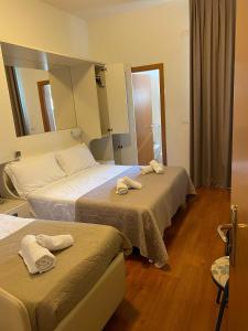two beds in a hotel room with towels on them at Hotel Butterfly Wellness & Spa in Rimini