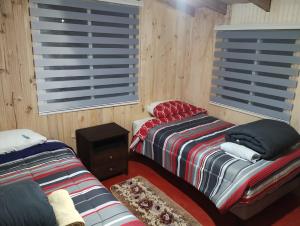 two beds in a room with wooden walls and windows at Residencial 4 estaciones in Futaleufú