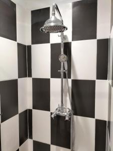 a shower with a lamp on a black and white tiled wall at La Framie basse in Albas