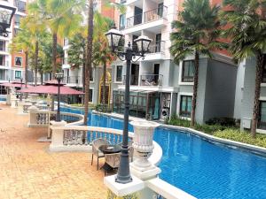 a hotel swimming pool with palm trees and a building at G63 Pool access room Espana Condo Resort Pattaya in Jomtien Beach