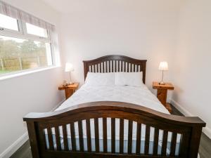 1 dormitorio con 1 cama grande de madera y 2 lámparas en 19A Lismenary Road en Ballyclare