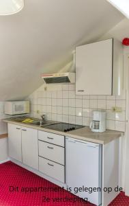 uma cozinha com armários brancos e um forno com placa de fogão em Appartementen Vouwere em Mechelen