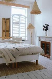 a white bedroom with a bed and a window at Superbe appartement avec cheminée in Verviers