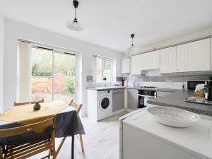 una cucina con armadi bianchi e un tavolo con una ciotola sul bancone di Pass the Keys Cosy 2BR Home in Walton a Walton-on-Thames