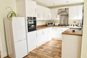 a white kitchen with white cabinets and a refrigerator at 3BD Gem in the Heart of Barnetby Le Wold in Barnetby le Wold