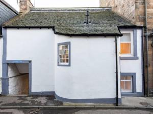 a small white building with a roof on a street at The Captain's Lookout - Cosy House with Sea Views in Anstruther