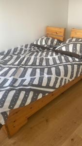 a bed with a black and white comforter at Especial fin de semana in Rødovre