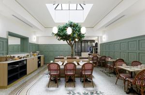 une salle à manger avec une table, des chaises et un arbre dans l'établissement Timhotel Palais Royal, à Paris