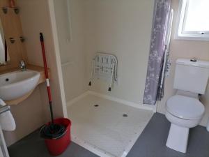 a bathroom with a toilet and a sink and a mop at Luxurious Wheelchair-Friendly holiday home at Kent Coast Holiday Park in Allhallows