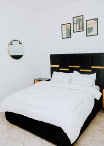 een slaapkamer met een groot wit bed met een zwart hoofdeinde bij LM Apartments in Dar es Salaam