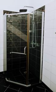 a shower in a bathroom with black tiles at LM Apartments in Dar es Salaam