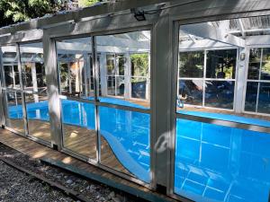 - une piscine dans une maison avec fenêtres dans l'établissement BOG Le Pommier - Cabañas con vista al lago y piscina climatizada, à Villa La Angostura