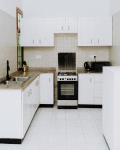 een keuken met witte kasten en een fornuis met oven bij LM Apartments in Dar es Salaam