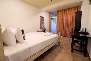 a bedroom with a white bed with a desk and a window at D Plus Resort Negombo in Negombo