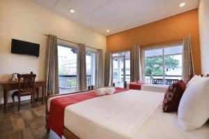 a bedroom with two beds and a desk and windows at D Plus Resort Negombo in Negombo