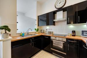 a kitchen with black cabinets and a clock on the wall at Pass the Keys Luxury 2 Apt in West Didsbury in Manchester