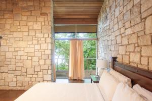 a bedroom with a stone wall and a large window at Frenchman's Cove Resort in Port Antonio