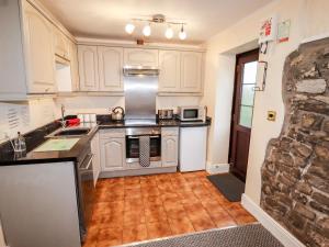 a kitchen with white cabinets and a stove top oven at Fern Cottage in Cardiff