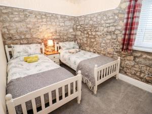 a bedroom with two beds and a stone wall at Fern Cottage in Cardiff