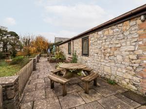 a picnic table and benches in front of a stone building at Fern Cottage in Cardiff