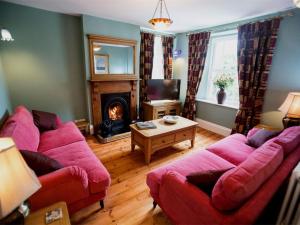 Withy Cottages في Langport: غرفة معيشة مع كنبتين حمراء ومدفأة