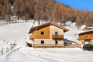 ein Blockhaus im Schnee mit einem Auto vor dem Haus in der Unterkunft Palipert Nature House in Livigno