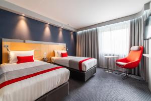 a hotel room with two beds and a red chair at Holiday Inn Express Ramsgate – Minster by IHG in Minster