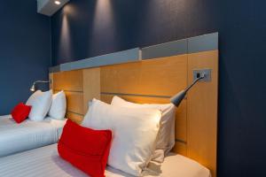 a bedroom with a bed with red and white pillows at Holiday Inn Express Ramsgate – Minster by IHG in Minster