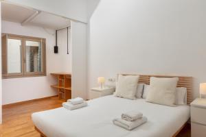 a bedroom with a large white bed with towels on it at Flateli Cort Reial 7 in Girona