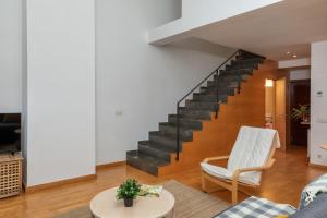 a living room with a staircase and a white chair at Flateli Cort Reial 7 in Girona