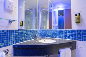 a blue tiled bathroom with a sink and a mirror at Holiday Inn Express Ramsgate – Minster by IHG in Minster