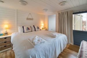 um quarto com uma cama branca com almofadas e uma janela em Flat 1, Baymount em Seaview