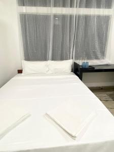 a bed with white sheets in a room with a window at BSG Stay Calangute Beach Road Goa Hotel in Calangute