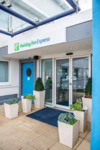 an office building with pots of plants in front of it at Holiday Inn Express Ramsgate – Minster by IHG in Minster
