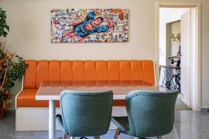 einen Esstisch mit einem orangenen Sofa und Stühlen in der Unterkunft Apartmány Gulliver in Mikulov