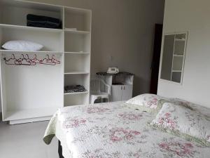 1 dormitorio con 1 cama y 1 habitación blanca con estanterías en Casa com piscina / Na quadra do mar Torres-RS en Torres