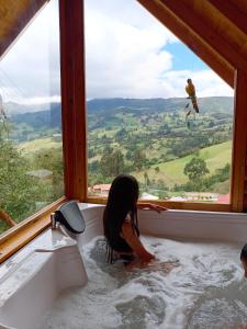 Una bambina in una vasca da bagno con una scimmia alla finestra di Glamping El Ocaso a Zipaquirá