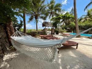 een hangmat op het strand naast een zwembad bij Villa Kipara - Beachfront with Private Pool in Pwani Mchangani