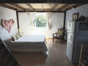 1 dormitorio con 1 cama, nevera y ventana en Mana en San Martín de los Andes