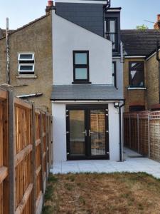 a white house with black doors and a fence at DaySpring White House - Dartford Kent in Kent