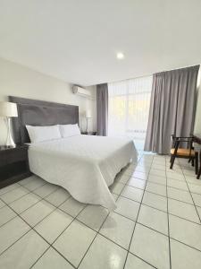 a bedroom with a white bed and a large window at Gran Hotel Paris in La Ceiba