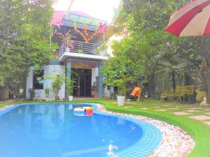 a swimming pool in front of a house with an umbrella at Homestay Happy Home Sóc Sơn in Hanoi